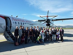 ÖSV-Team mit Hopsi und Gerhard Widmann, dem Geschäftsführer des Flughafen Graz, vor dem Flugzeug.