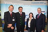 Roland Hladin, Heinz Kaller, Melanie Frühwirt und Gerhard Widmann vor einem Flughafen Graz Plakat