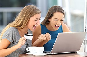 Zwei Frauen am Laptop mit Kreditkarte.